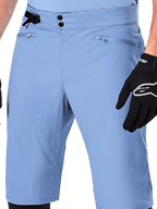 Calções Alpinestars A-Dura, calções de BTT em azul Infinity, grande plano da cintura com fecho de pressão duplo, ajuste lateral regulável e bolsos com fecho e forro em rede, usados com uma luva Alpinestars preta