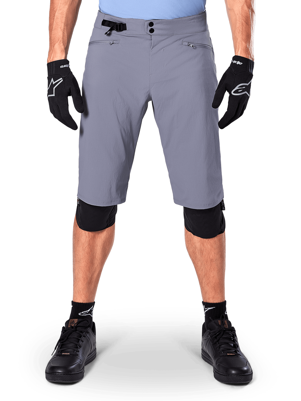 Calções Alpinestars A-Dura, calções de mountain bike, cinzento-escuro, usados com luvas e joelheiras pretas Alpinestars, com fecho duplo de pressão e bolsos com fecho e forro em rede, tecido durável com elasticidade bidirecional para ciclismo fora de estrada
