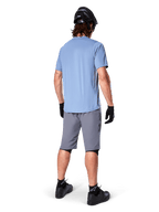 Calções Alpinestars A-Dura, calções de BTT cinzento escuro, vista traseira, usados com camisola de manga curta azul claro e capacete de BTT preto, luvas e meias pretas com sapatos pretos, equipamento funcional e durável para ciclismo todo-o-terreno
