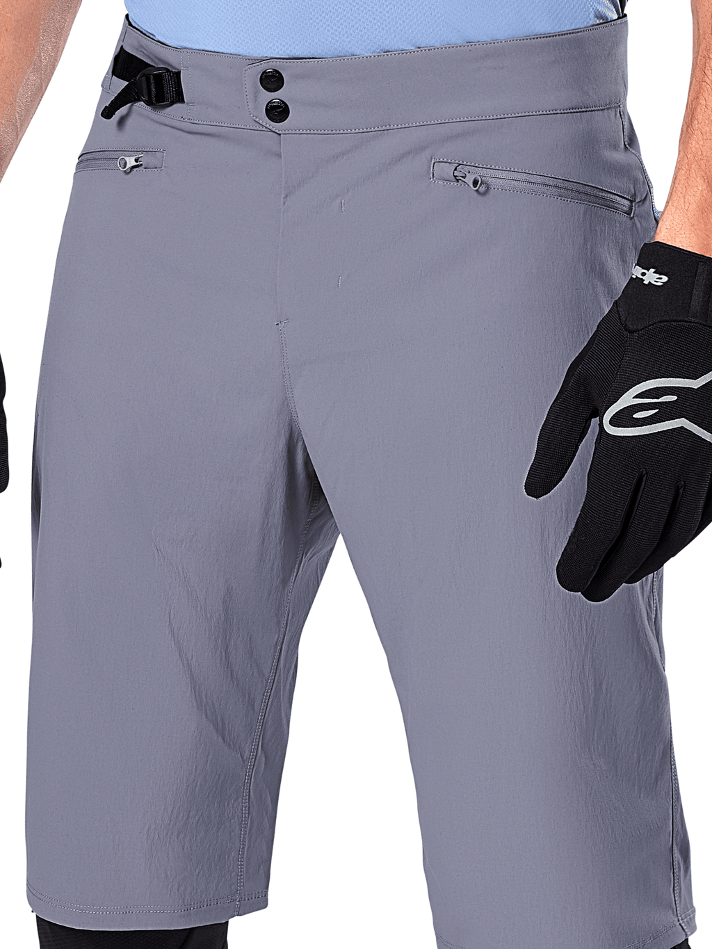 Calções Alpinestars A-Dura, calções de MTB, cinzento escuro, vista detalhada da cintura mostrando fecho de pressão duplo, ajustador lateral e bolsos com fecho, combinados com luvas de ciclismo pretas, vestuário durável para mountain bike