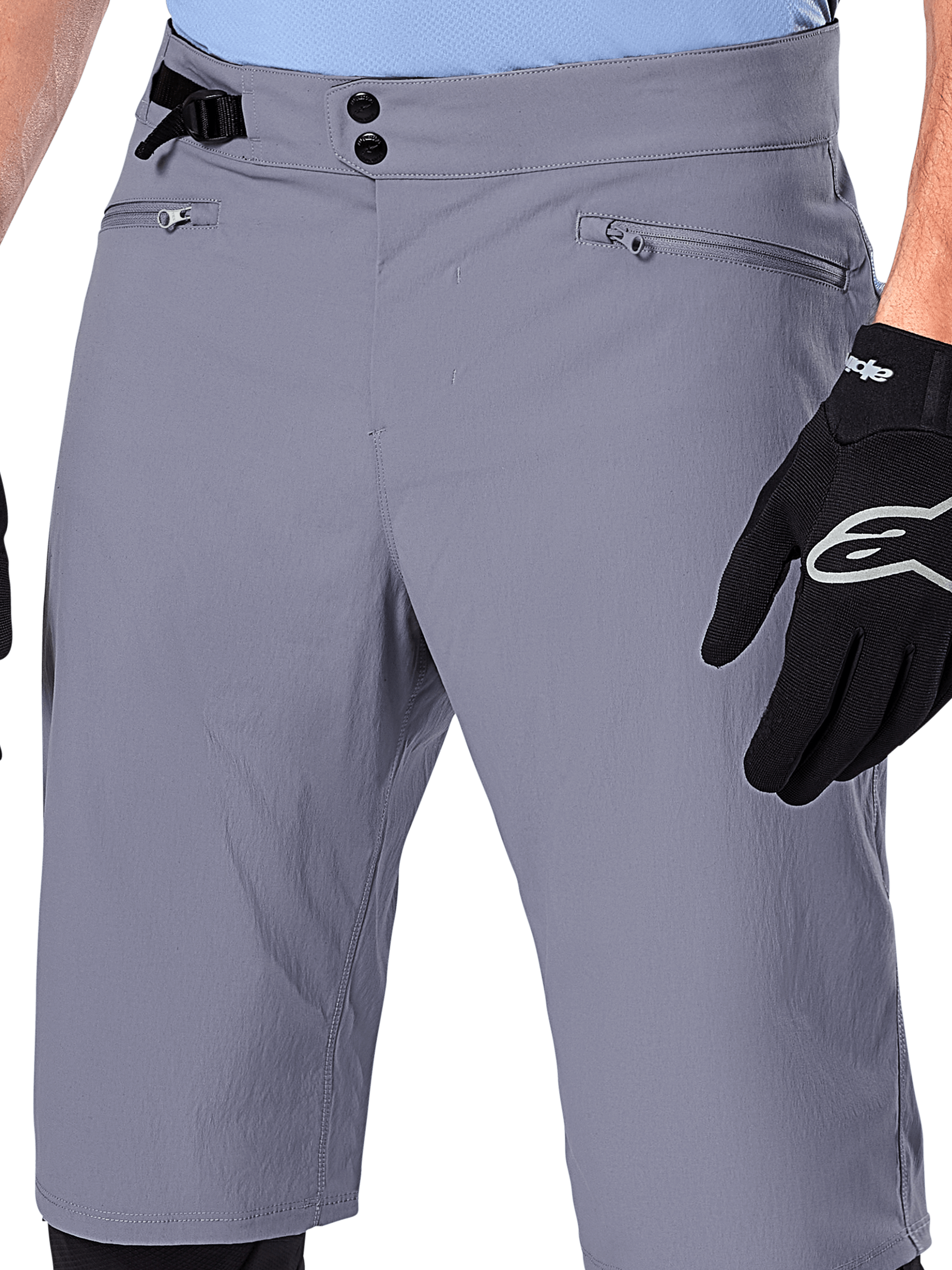 Calções Alpinestars A-Dura, calções de MTB, cinzento escuro, vista detalhada da cintura mostrando fecho de pressão duplo, ajustador lateral e bolsos com fecho, combinados com luvas de ciclismo pretas, vestuário durável para mountain bike