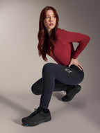 Calças Térmicas Alpinestars Stella A-Dura, calças de MTB para mulher, pretas, usadas por uma modelo numa pose agachada com uma camisola de manga comprida bordeaux e sapatos de ciclismo pretos, apresentando um logótipo de estrela branca na coxa, construção durável e quente para ciclismo em clima frio