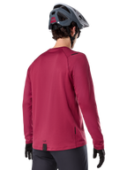 Alpinestars A-Dura Thermal Jersey, camisola de BTT de manga comprida, bordeaux, vista traseira num modelo com capacete de BTT cinzento e luvas pretas, com cauda traseira alongada e pequenos detalhes do logótipo, concebida para a prática de trilhos em climas frios.