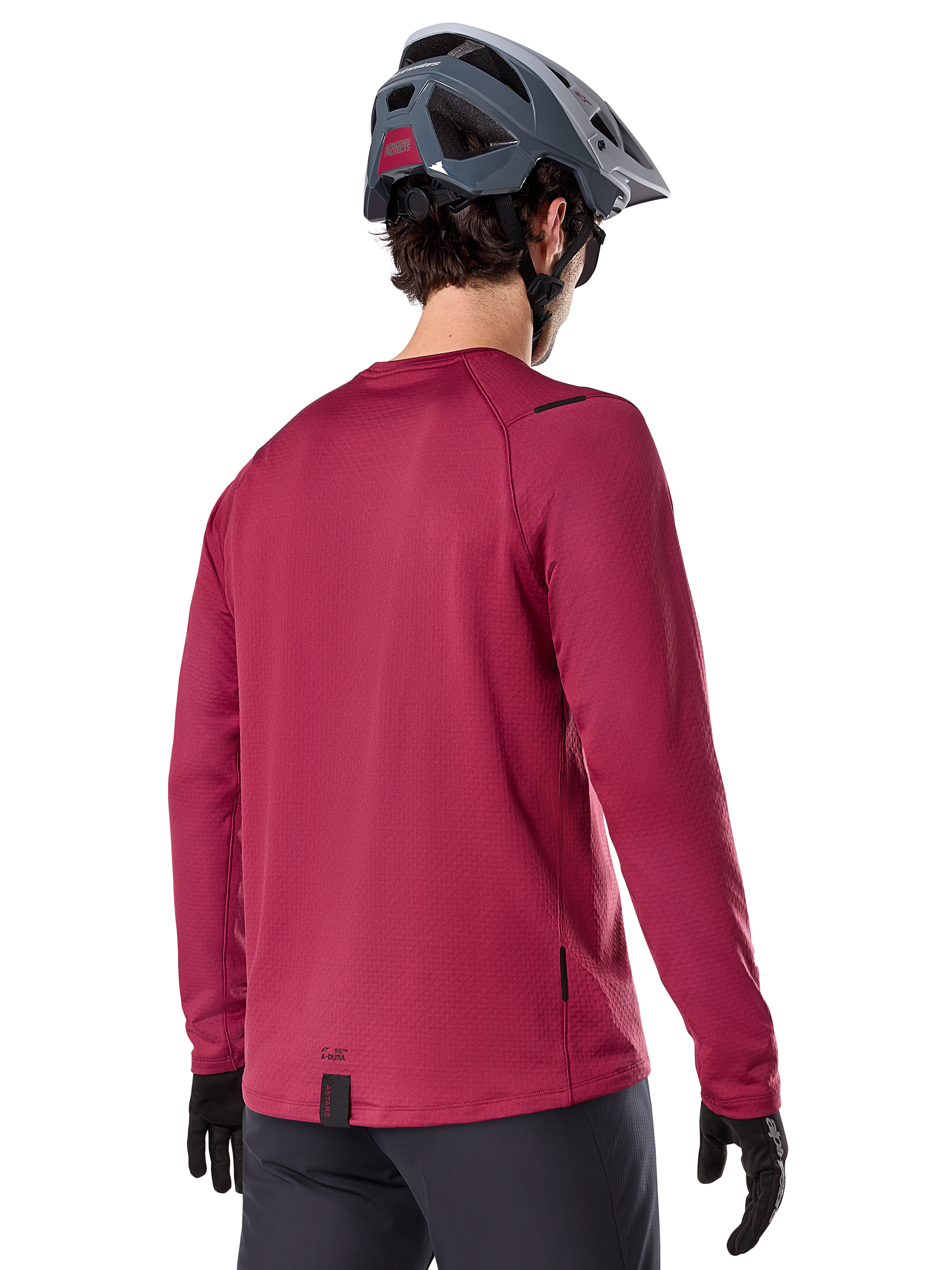 Alpinestars A-Dura Thermal Jersey, camisola de BTT de manga comprida, bordeaux, vista traseira num modelo com capacete de BTT cinzento e luvas pretas, com cauda traseira alongada e pequenos detalhes do logótipo, concebida para a prática de trilhos em climas frios.