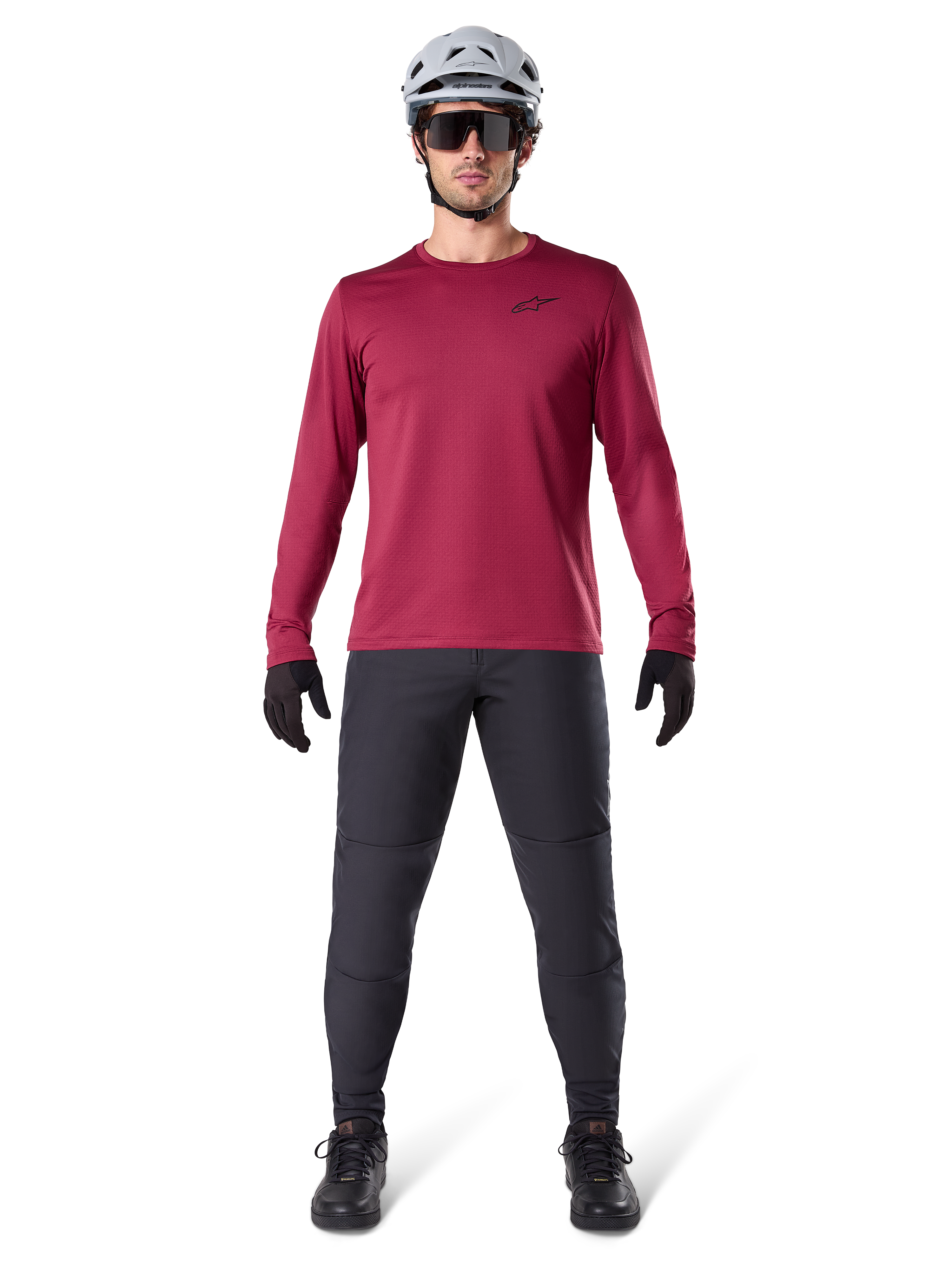 Modelo masculino a usar a Alpinestars A-Dura Thermal Jersey em Vermelho, camisola de ciclismo de manga comprida isolada, combinada com calças de BTT cinzento escuro, capacete branco, óculos de sol pretos e luvas pretas, equipamento profissional de BTT para tempo frio