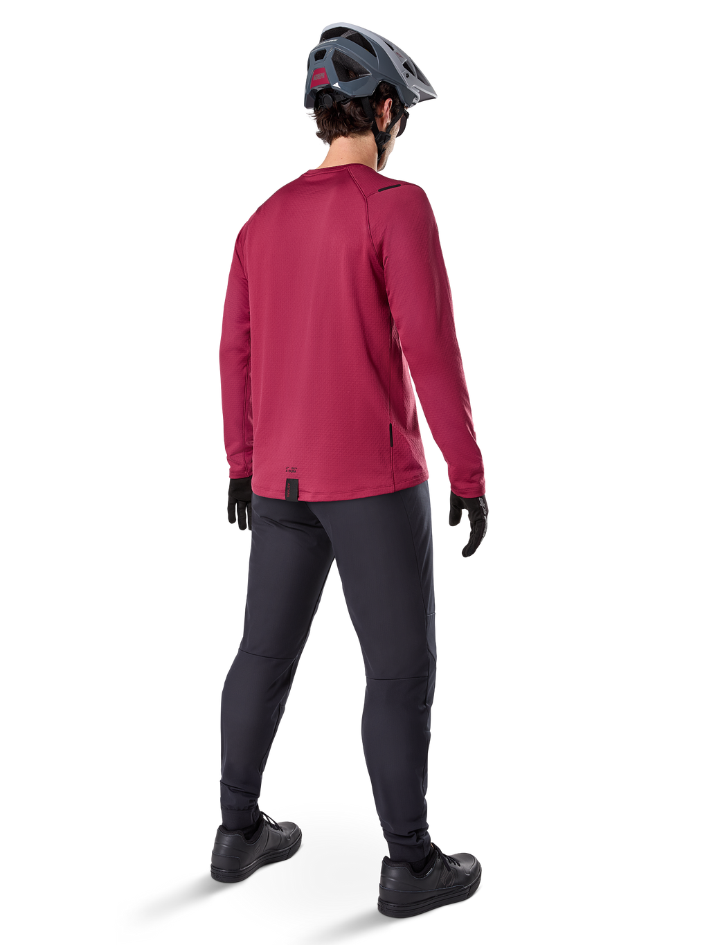 Camisola Térmica Alpinestars A-Dura, camisola de ciclismo de manga comprida cor borgonha, vista traseira, usada com calças de BTT pretas e capacete cinzento, com bainha traseira alongada para maior cobertura, equipamento de BTT para clima frio