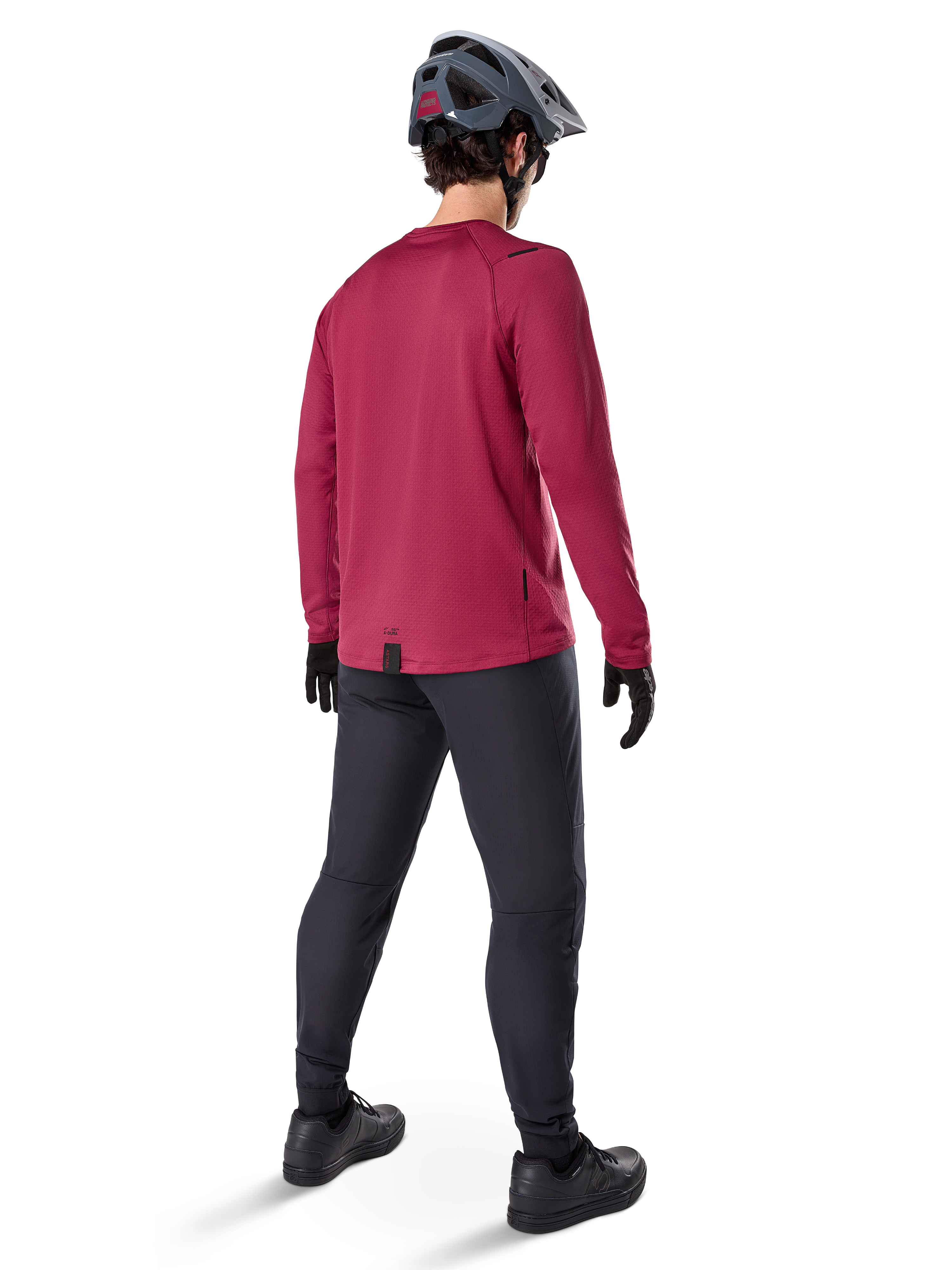 Camisola Térmica Alpinestars A-Dura, camisola de ciclismo de manga comprida cor borgonha, vista traseira, usada com calças de BTT pretas e capacete cinzento, com bainha traseira alongada para maior cobertura, equipamento de BTT para clima frio