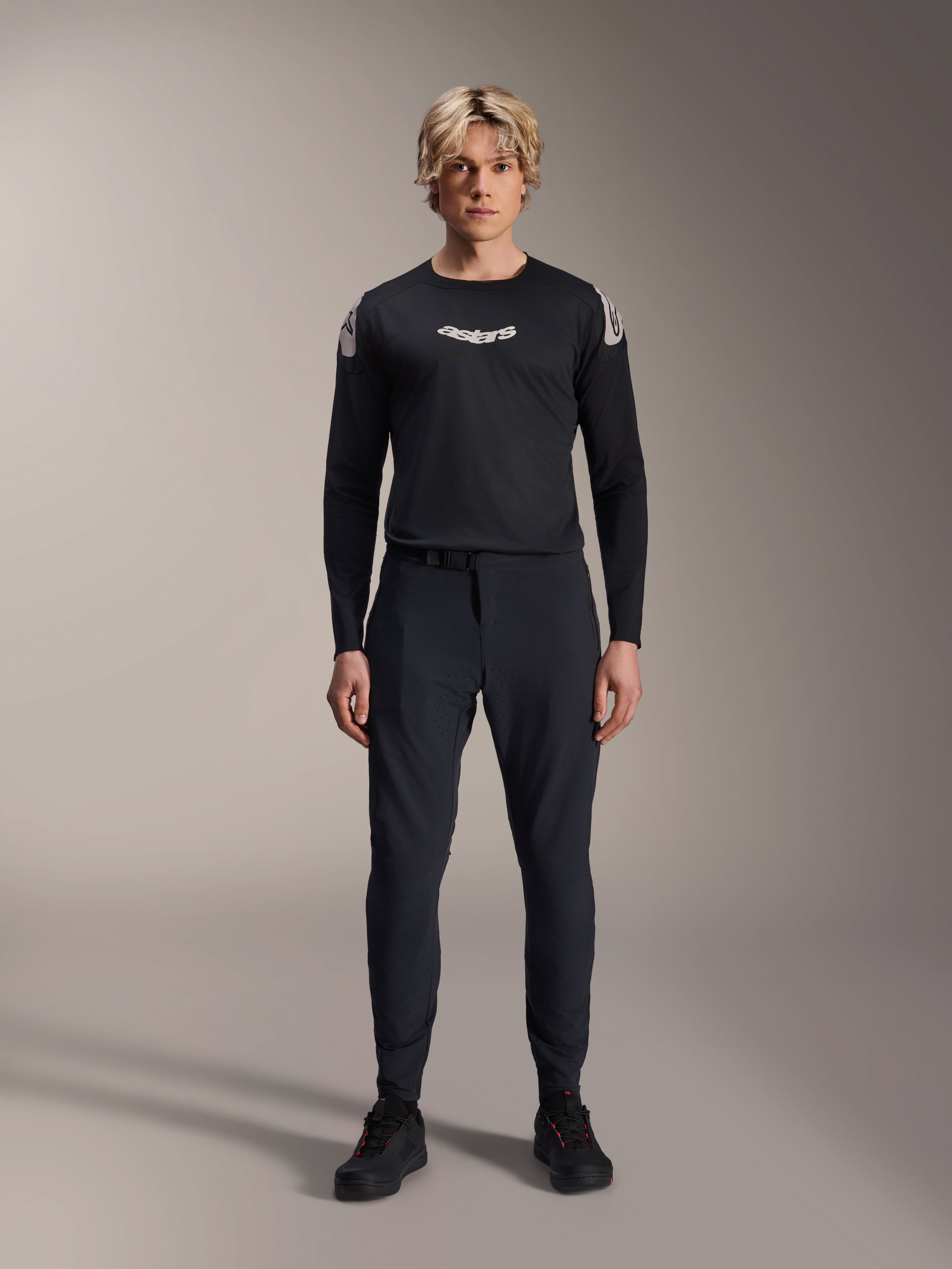 Alpinestars A-Aria Elite Pants, calças de BTT Black Titanium, usadas por um modelo masculino com uma camisola de manga comprida preta e sapatilhas a condizer, design de performance com ajuste slim e fecho de fivela magnética, vestuário técnico de mountain bike