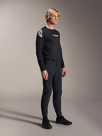 Male model wearing Alpinestars A-Aria Elite Pants in Black Titanium and Aria Polartec Elite LS Jersey, black mountain bike performance gear, featuring laser-perforated ventilation and magnetic buckle closure on the pants, long-sleeve jersey with white logos, complete off-road cycling outfit