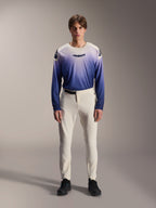Alpinestars A-Aria Elite Pants, calças de performance para MTB em cor cru, calças de ciclismo off-white com painéis perfurados a laser nas coxas e fivela magnética, combinadas com camisola de manga comprida em azul degradê e sapatos pretos, ajuste de performance para trilhos