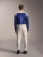 Alpinestars A-Aria Polartec Maker Elite Long Sleeve Jersey, azul Baja Blue e off-white, vista traseira de modelo a usar equipamento técnico de BTT, incluindo calças off-white com a marca Alpinestars na parte inferior das pernas, conjunto de ciclismo de performance para trilhos fora de estrada
