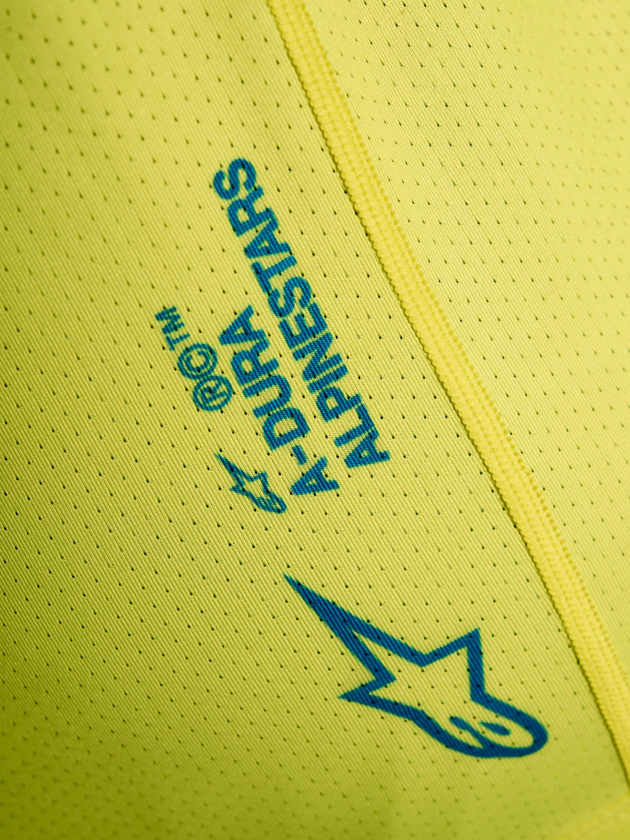 Yellow Fluo A-Dura Air Jersey detail featuring breathable mesh fabric and blue Alpinestars logo graphics.