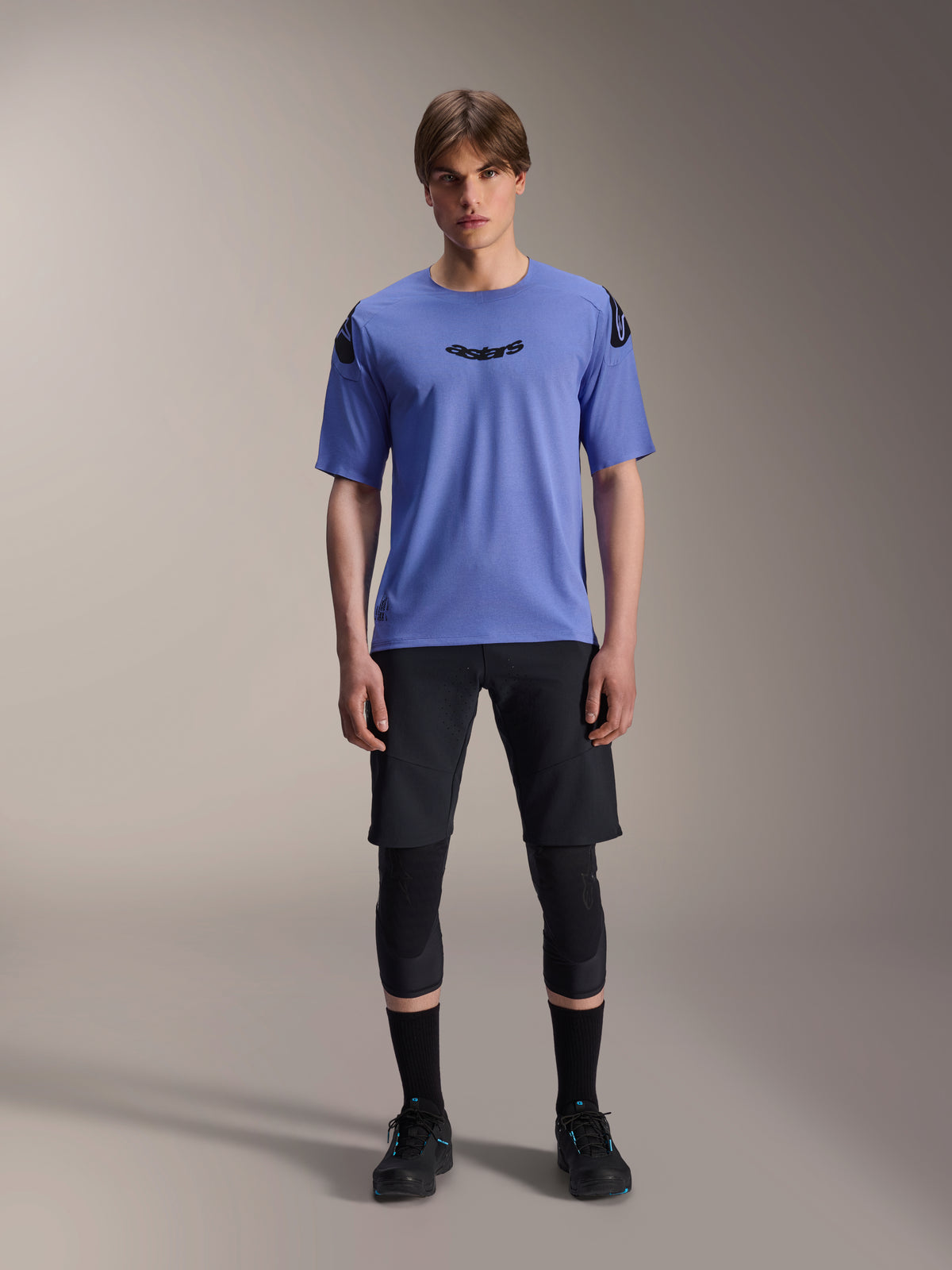 Alpinestars A-Aria Lite Short, calções de BTT para homem, pretos, usados com camisola de manga curta lilás e joelheiras pretas, vestuário de BTT de alta performance