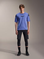 Alpinestars A-Aria Elite Shorts, calções de BTT, Black Titanium, usados com camisola azul de manga curta, joelheiras e sapatos de ciclismo pretos, fotografia de corpo inteiro em estúdio, vestuário de performance para BTT