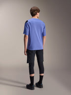 Camisola de manga curta Alpinestars A-Aria Polartec Elite em Baja Blue, vista traseira num modelo masculino, combinada com calções de MTB pretos e joelheiras, com ajuste de performance e bainha traseira descaída para trail riding.