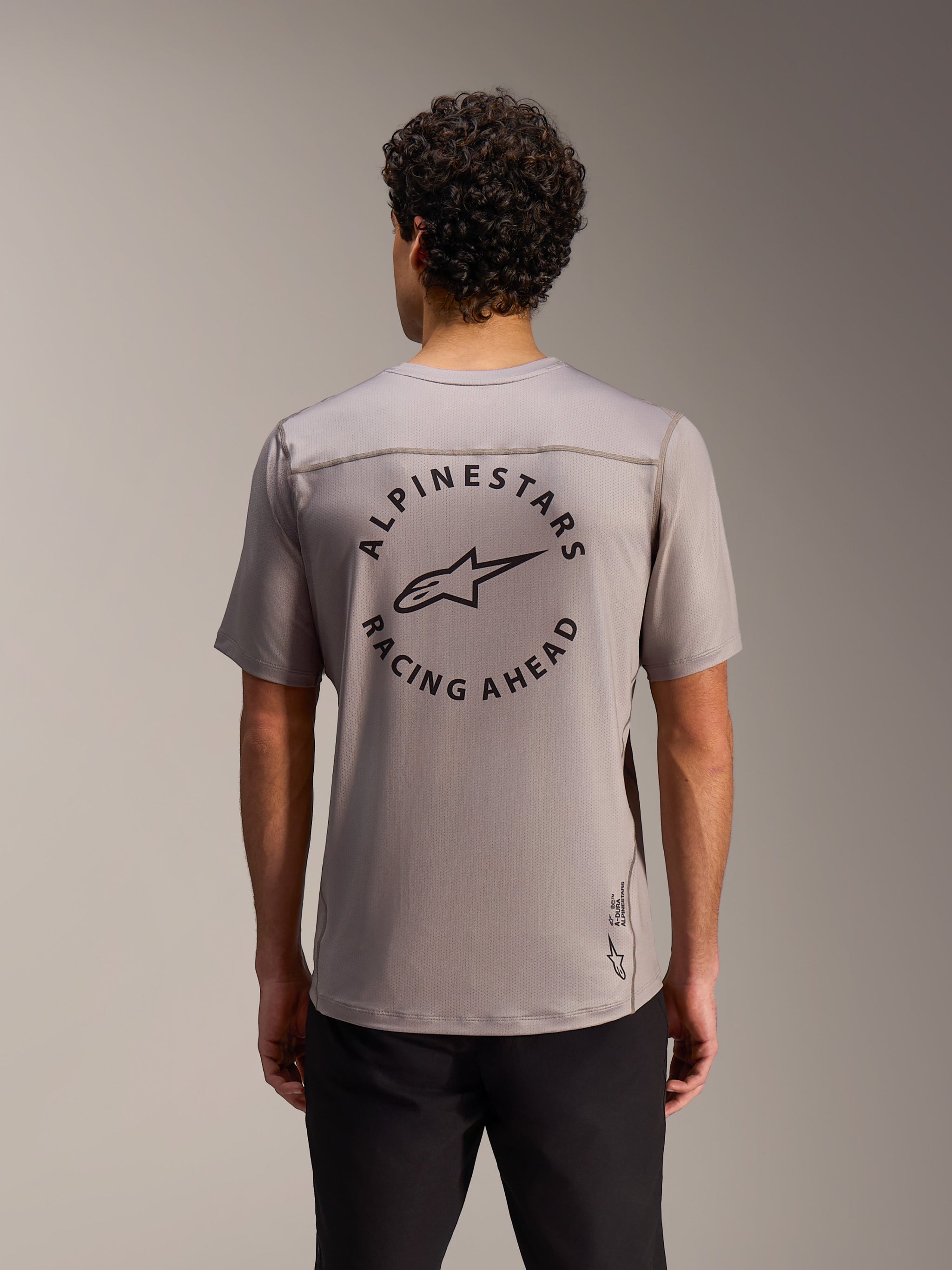 Camisola A-Dura Air cinzenta com logótipo circular Alpinestars Racing Ahead nas costas em malha respirável.