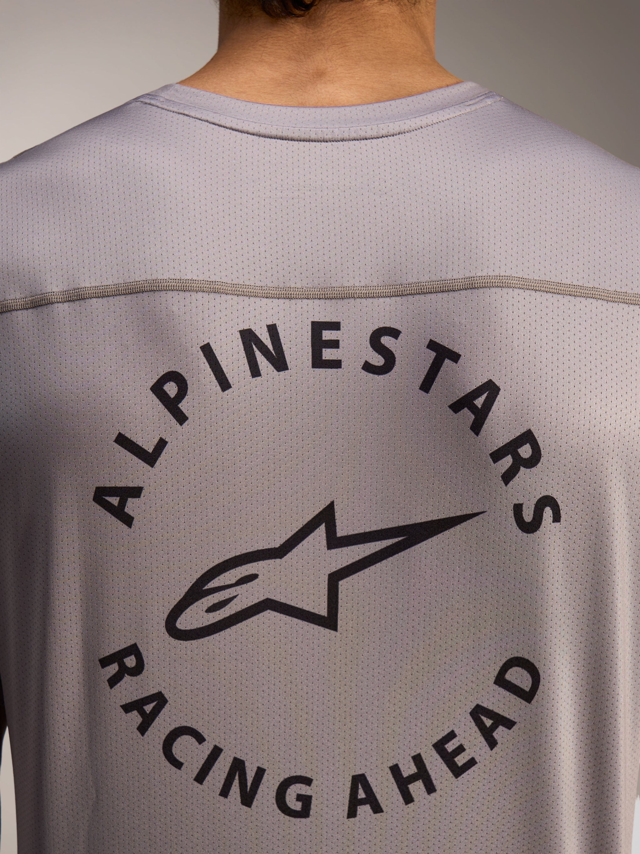 Camisola A-Dura Air cinzenta, detalhe das costas com logótipo Alpinestars Racing Ahead em tecido mini mesh respirável.