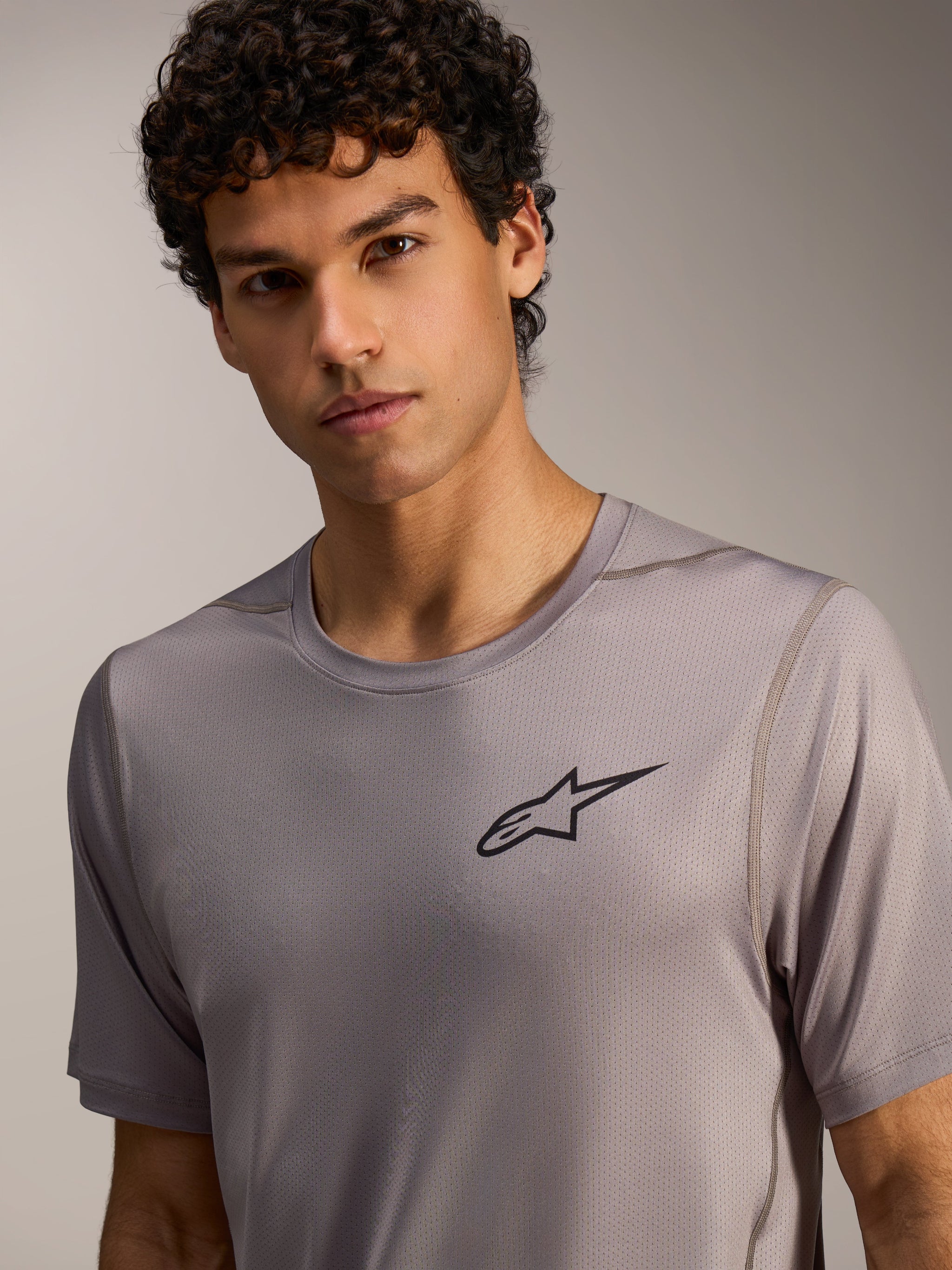 Camisola Alpinestars A-Dura Air cinzenta de mangas curtas, com tecido mini-mesh respirável e logótipo Astars no peito.