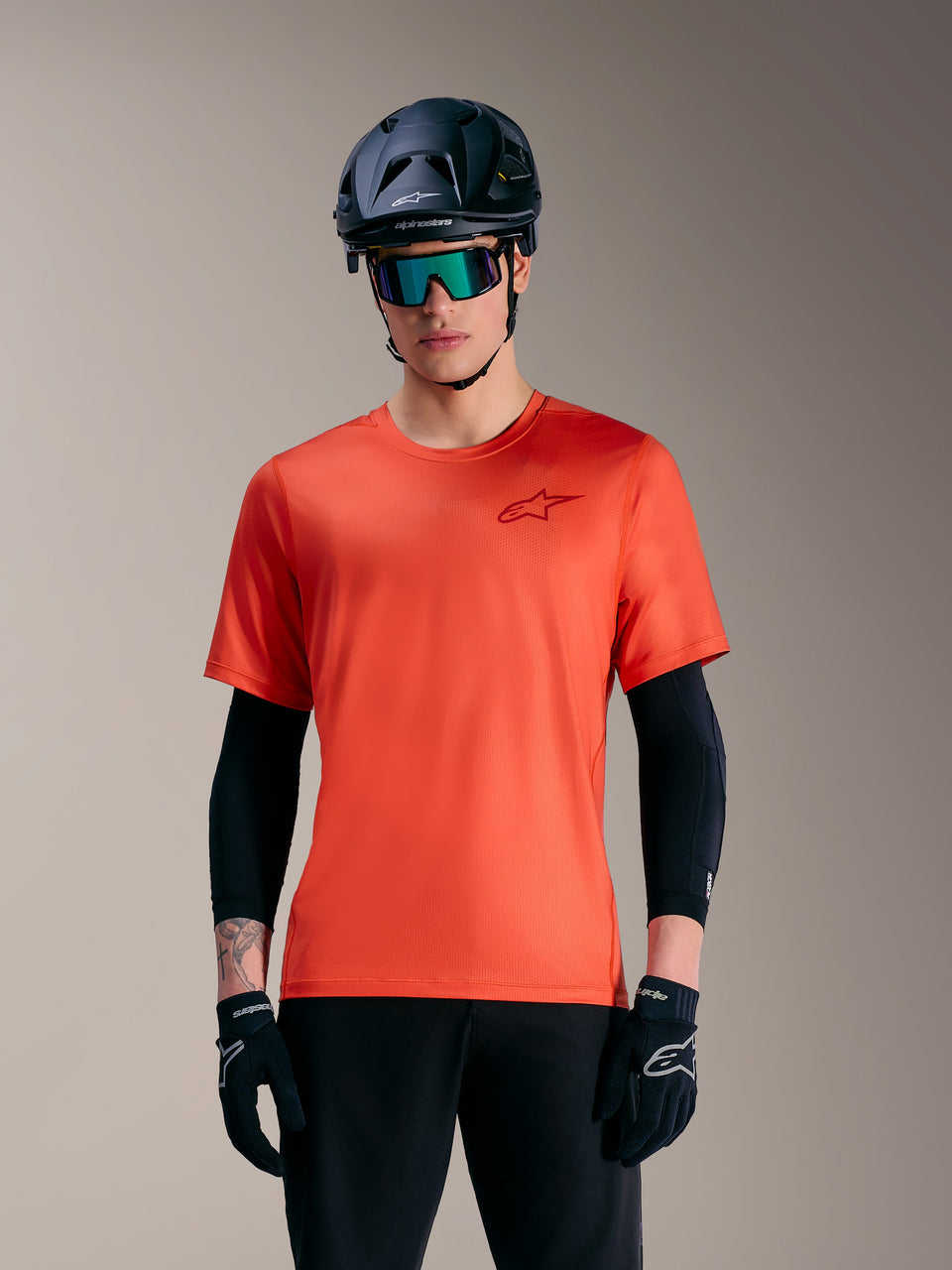 Alpinestars A-Dura Air de manga curta laranja, camisola MTB respirável com logótipo, usada com capacete e óculos.