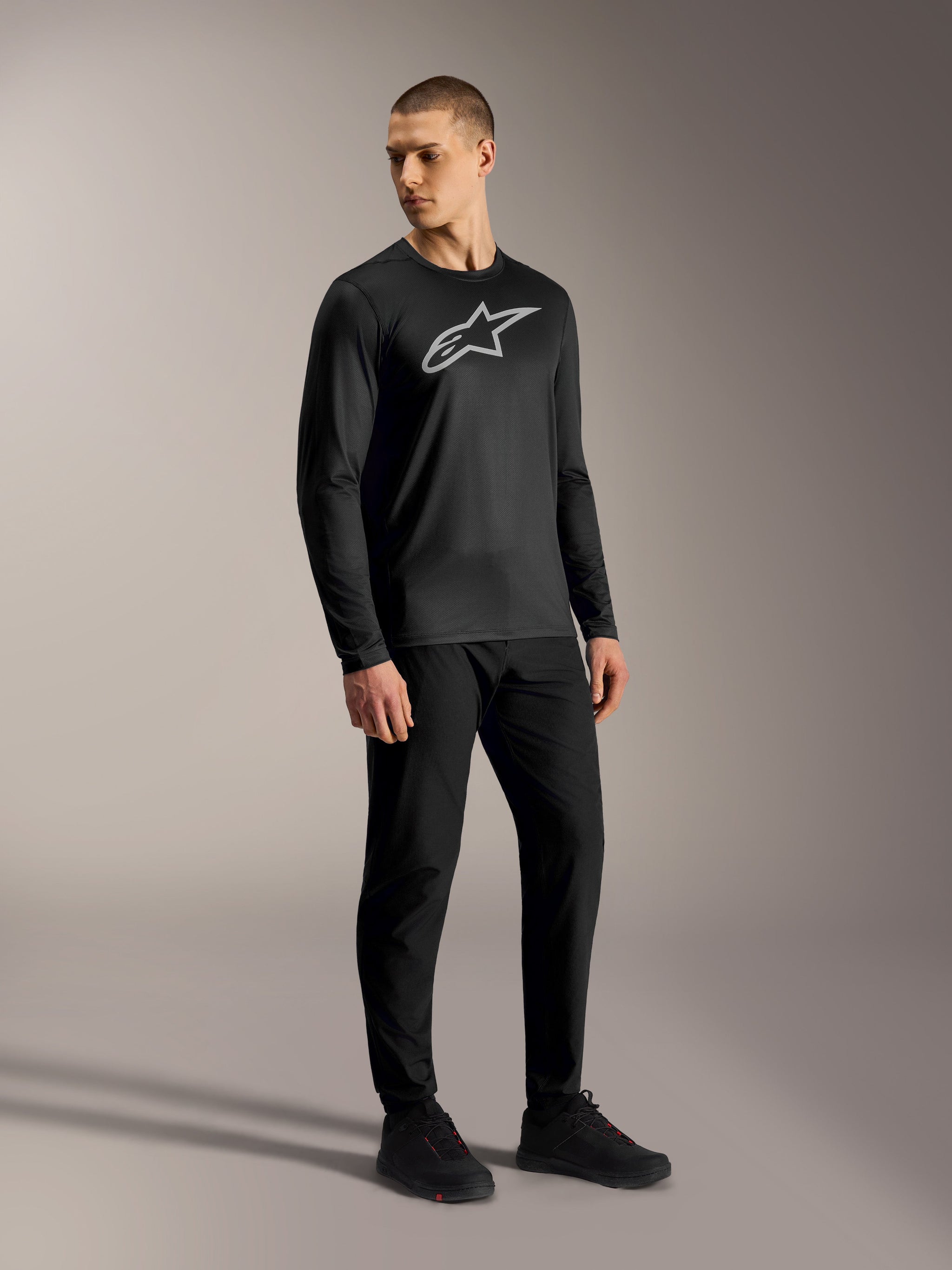 Black A-Dura Ride Long Sleeve Jersey with a grey Astars logo, worn by a model as high-performance mountain bike apparel.