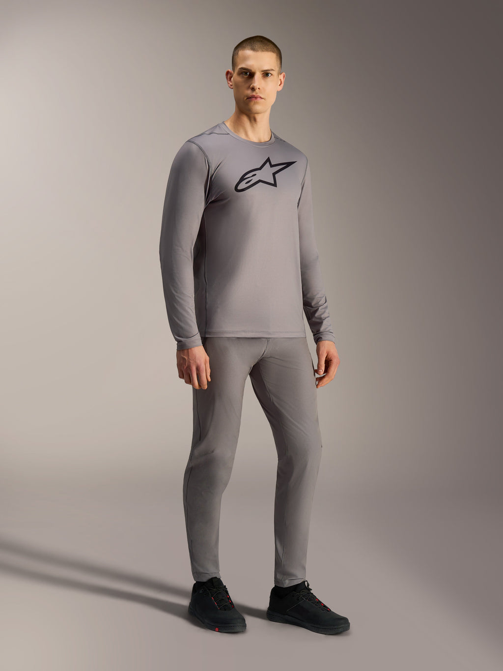 Camisola cinzenta A-Dura Ride de mangas compridas com logótipo preto, modelada num visual completo de BTT.