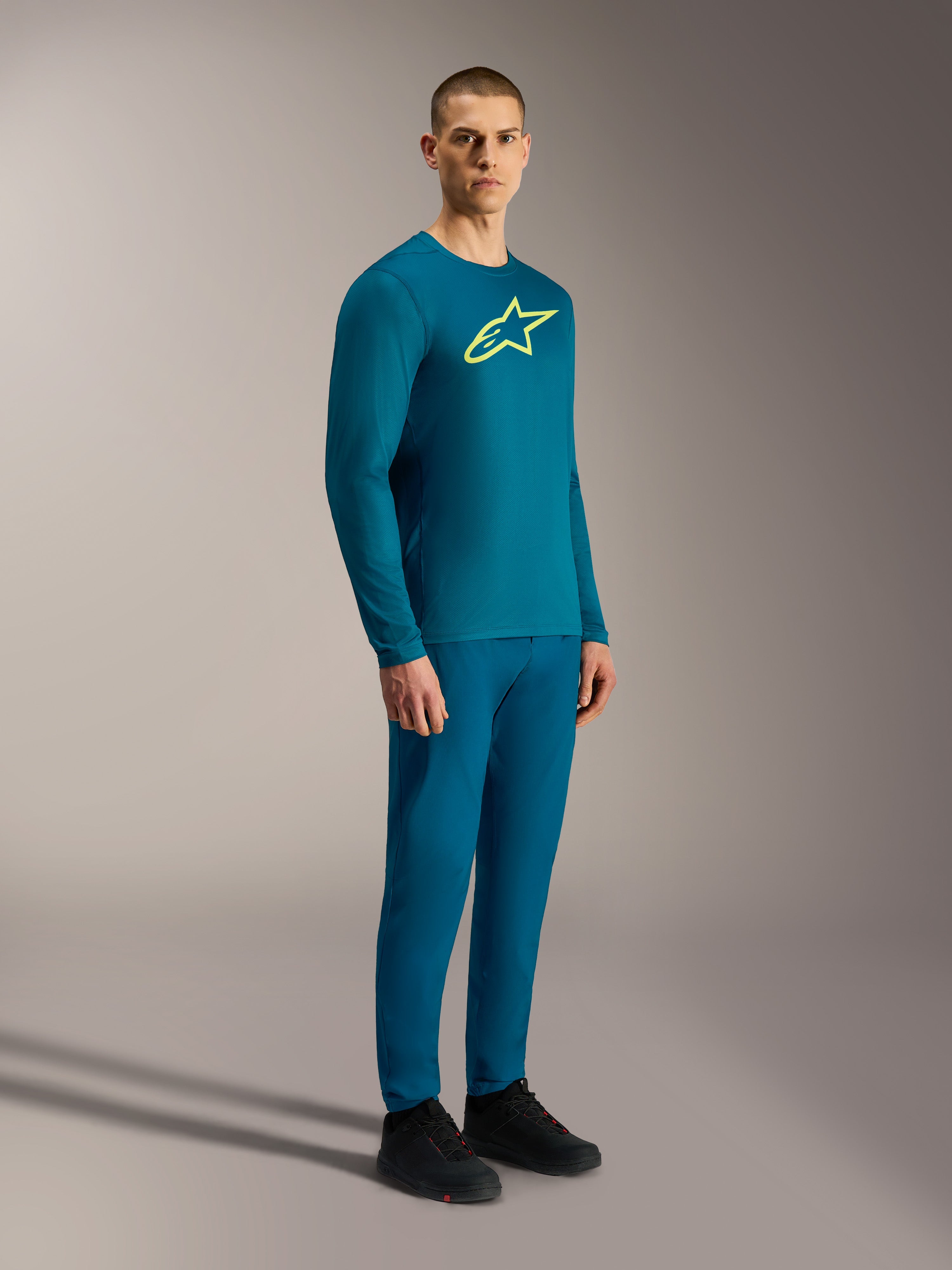 Camisola A-Dura Ride de mangas compridas azul esverdeado, com logótipo Astars amarelo e calças de BTT a condizer.
