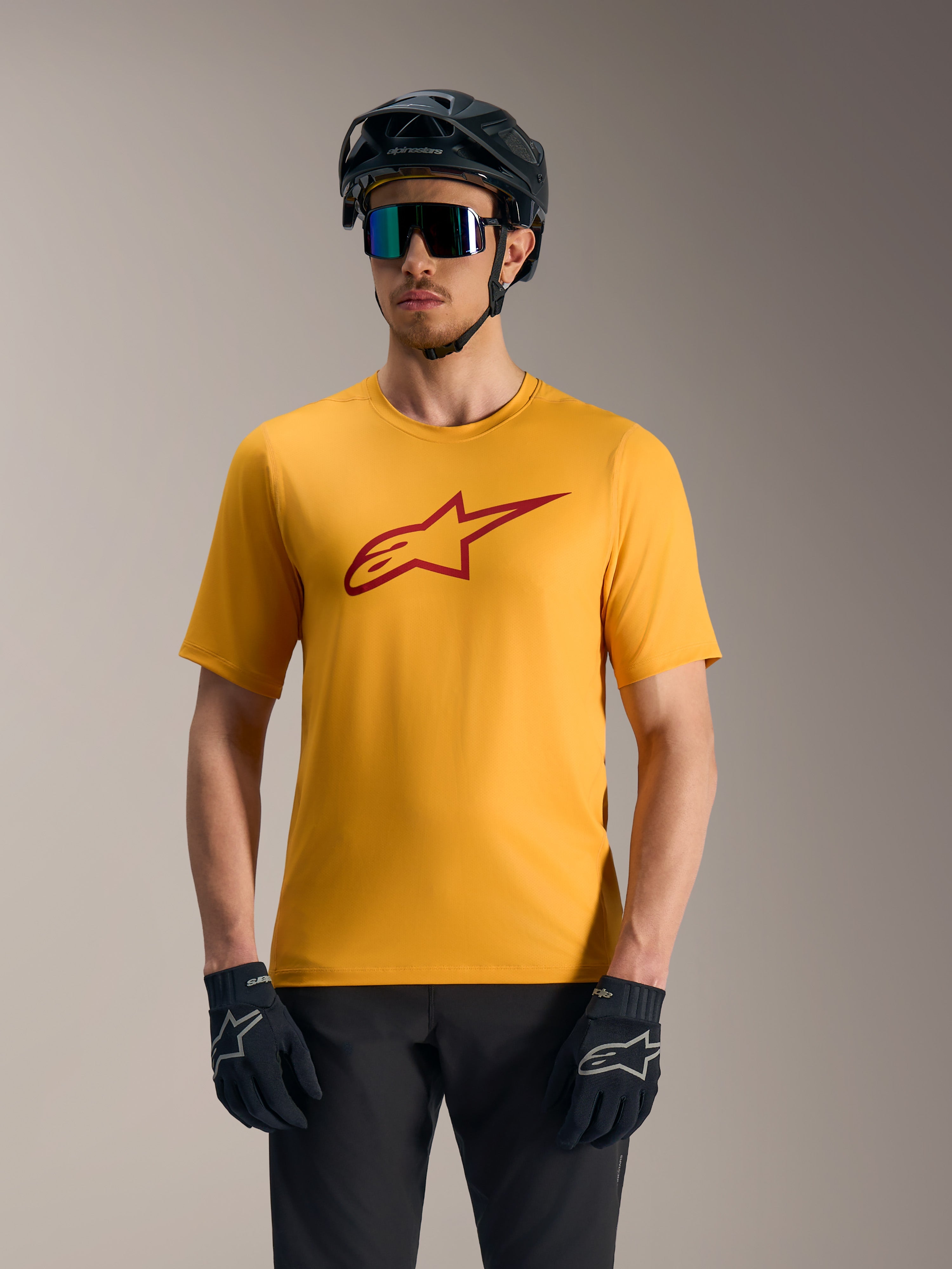 Camisola Alpinestars A-Dura Ride laranja de mangas curtas, com logótipo Astars vermelho, capacete e luvas de BTT.