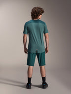 Camisola de manga curta Alpinestars A-Dura Lipan em Silver Pine, vista traseira a mostrar os painéis de jacquard texturizados nos ombros e a bainha com cauda mais longa, usada com calções de bicicleta de montanha em verde escuro a condizer e calçado preto.