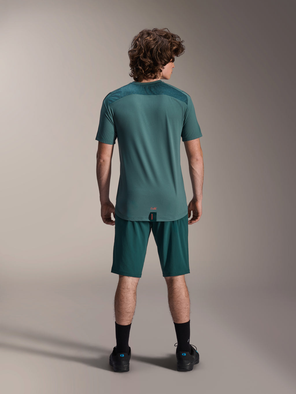 Calções Alpinestars A-Dura e Jersey A-Dura Lipan SS, verde Dark Pine, vista traseira num modelo, vestuário de performance para BTT com jersey de manga curta e calções a condizer, equipamento de ciclismo fora de estrada