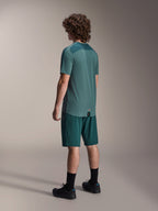Modelo masculino a usar a Camisola de Manga Curta Alpinestars A-Dura Lipan em Silver Pine, visto de costas, combinada com calções de BTT verde escuro a condizer, meias e sapatos pretos, com um painel superior texturizado nas costas e uma bainha traseira mais comprida para maior cobertura.