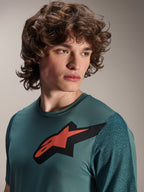 Camisola Alpinestars A-Dura Lipan, camisola de BTT de manga curta, Silver Pine, apresenta um logótipo Astars proeminente a vermelho e preto no peito, mangas em jacquard texturado, retrato em grande plano de modelo a usar equipamento de ciclismo de alta performance