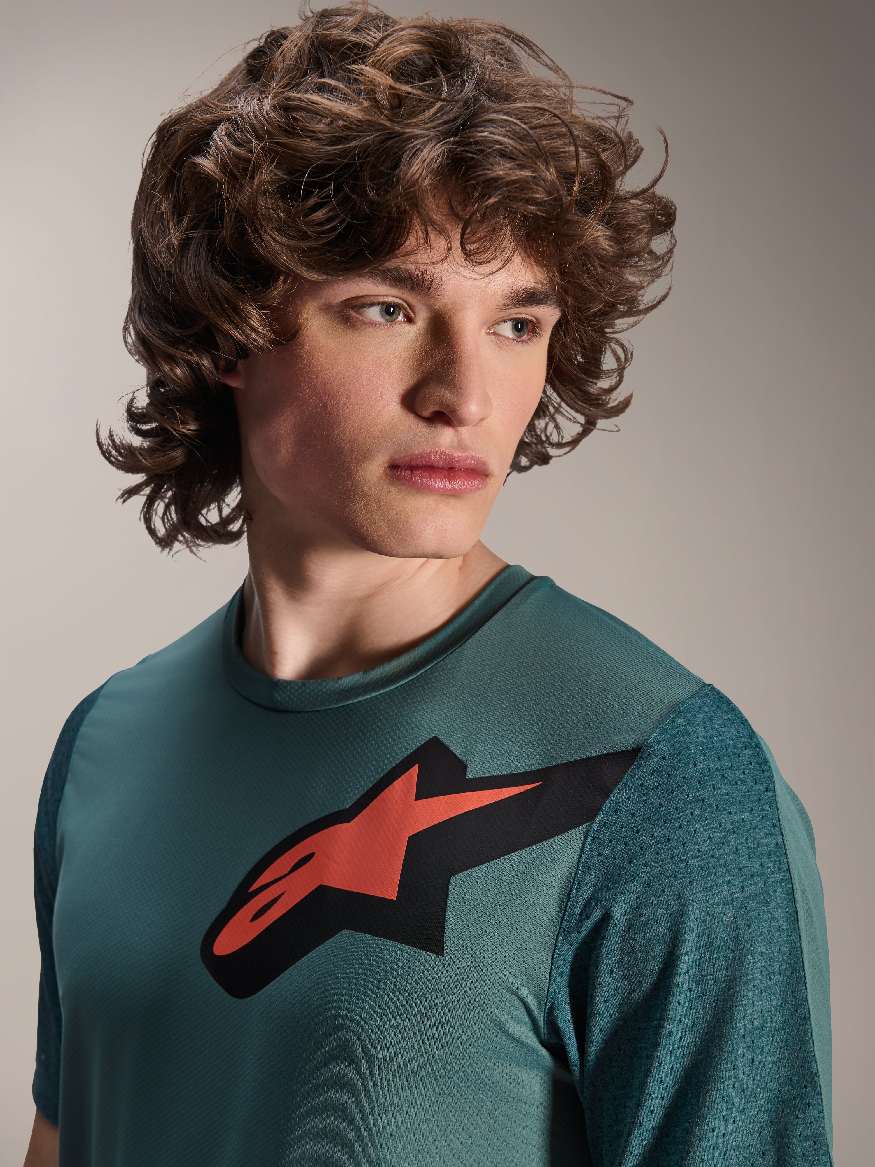 Camisola Alpinestars A-Dura Lipan, camisola de BTT de manga curta, Silver Pine, apresenta um logótipo Astars proeminente a vermelho e preto no peito, mangas em jacquard texturado, retrato em grande plano de modelo a usar equipamento de ciclismo de alta performance