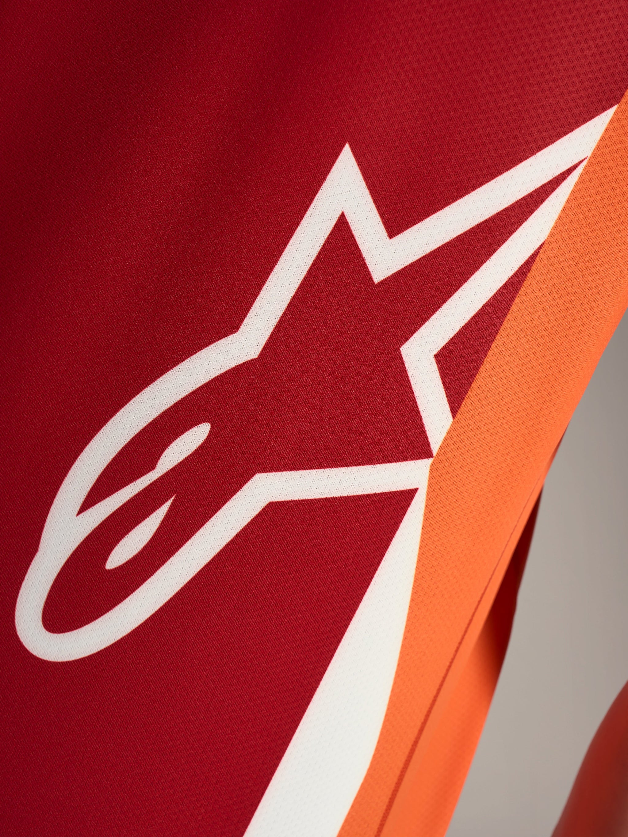 White Astars logo on orange A-Dura Race Jersey, showing the breathable jacquard mesh fabric and performance detailing.