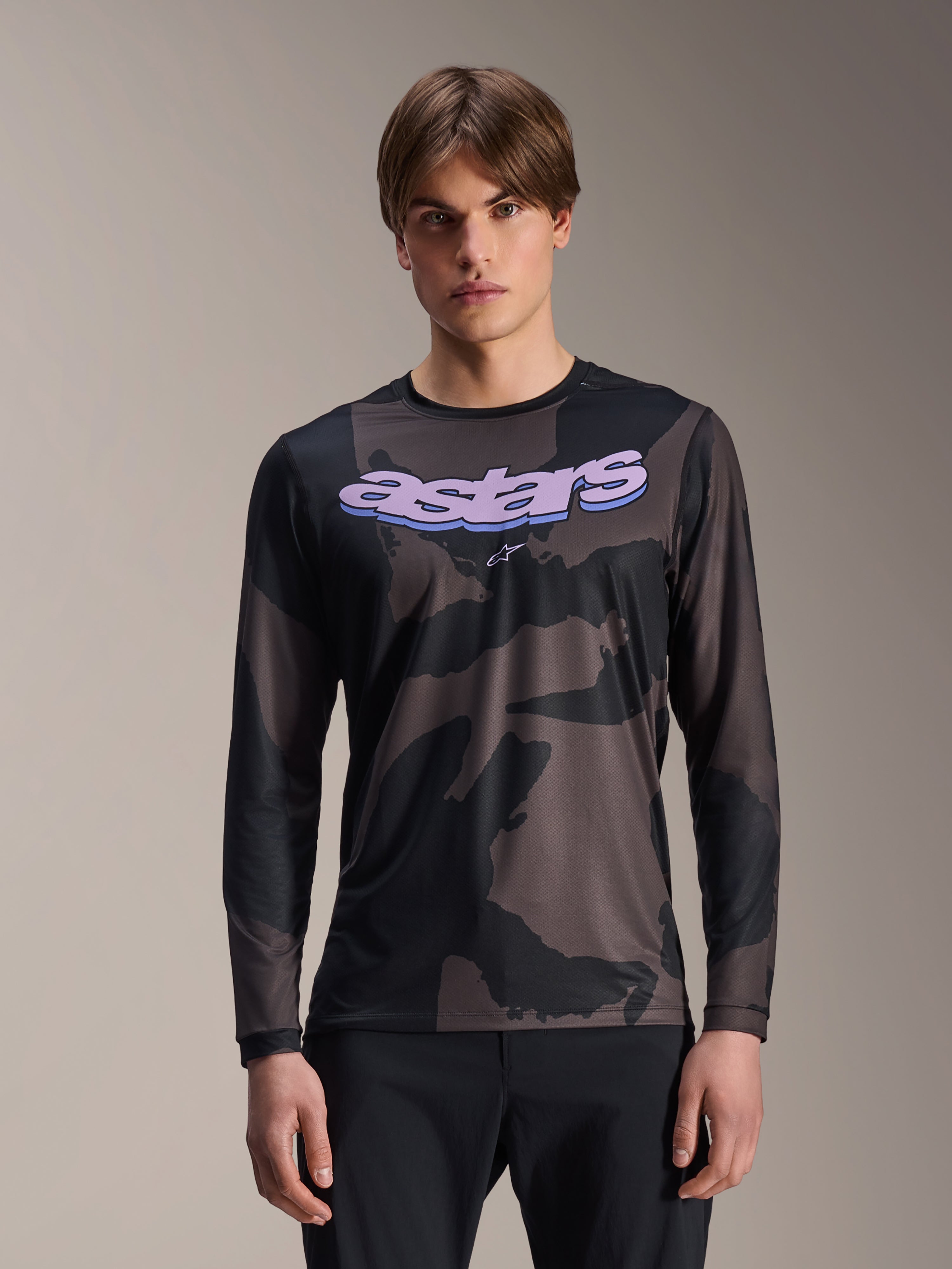 Alpinestars A-Dura Hollow Camo Jersey de manga comprida, camisola de BTT, padrão camuflado preto e cinzento, gráfico 'astars' roxo no peito, modelo com calças pretas, design casual de performance