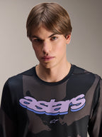 Alpinestars A-Dura Hollow Camo Jersey - Long Sleeve, camuflado preto com grafismo 'astars' roxo no peito, fotografia de estúdio de modelo masculino a usar vestuário de BTT, estilo casual e técnico de bicicleta de montanha