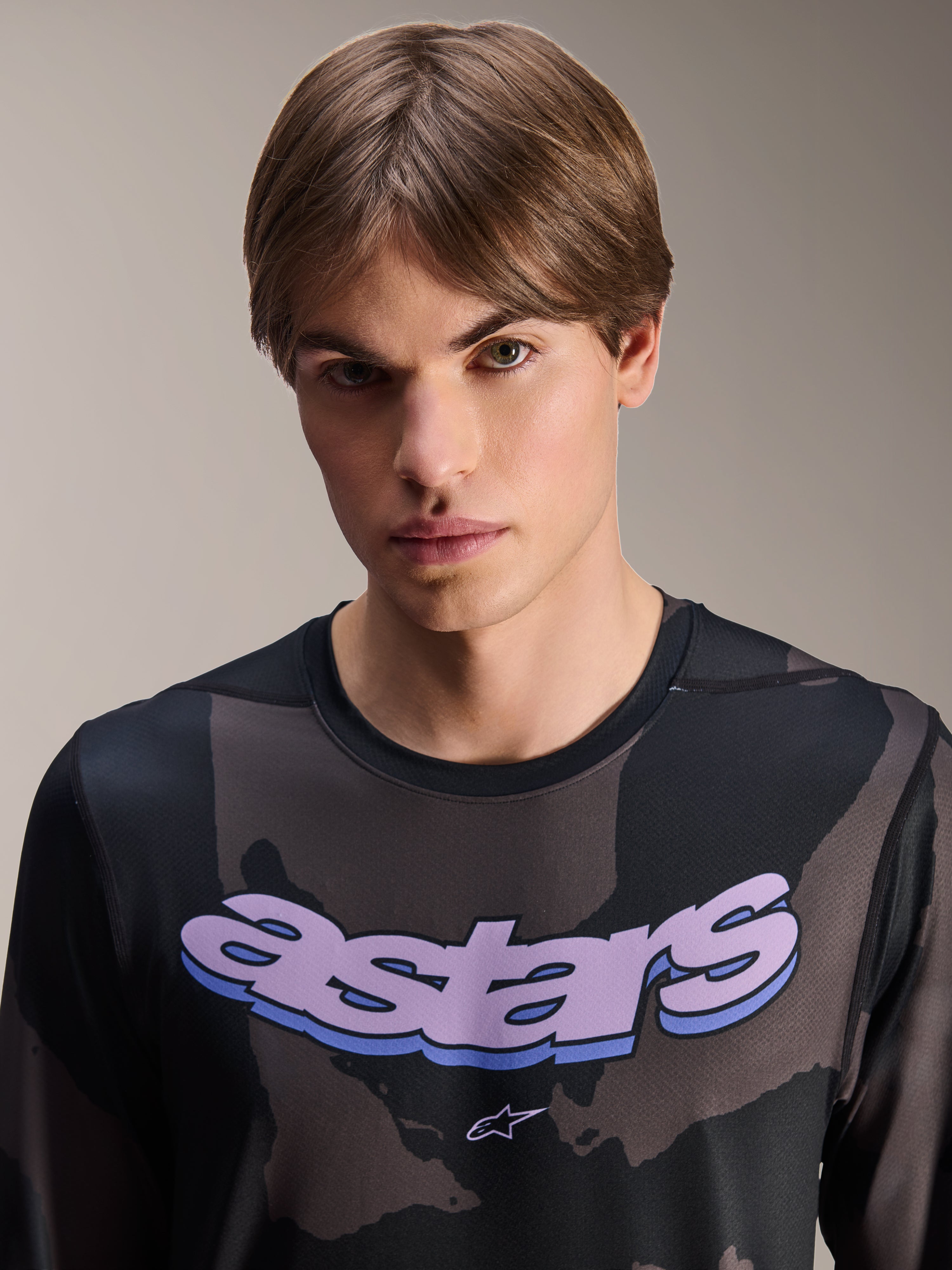 Alpinestars A-Dura Hollow Camo Jersey - Long Sleeve, camuflado preto com grafismo 'astars' roxo no peito, fotografia de estúdio de modelo masculino a usar vestuário de BTT, estilo casual e técnico de bicicleta de montanha