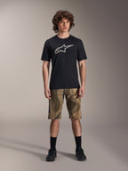 Camisola de Manga Curta Alpinestars A-Dura Astar, preta com logótipo Astars branco grande no peito, vestida por um modelo com calções de BTT camuflados e sapatilhas de ciclismo pretas, vestuário casual de BTT