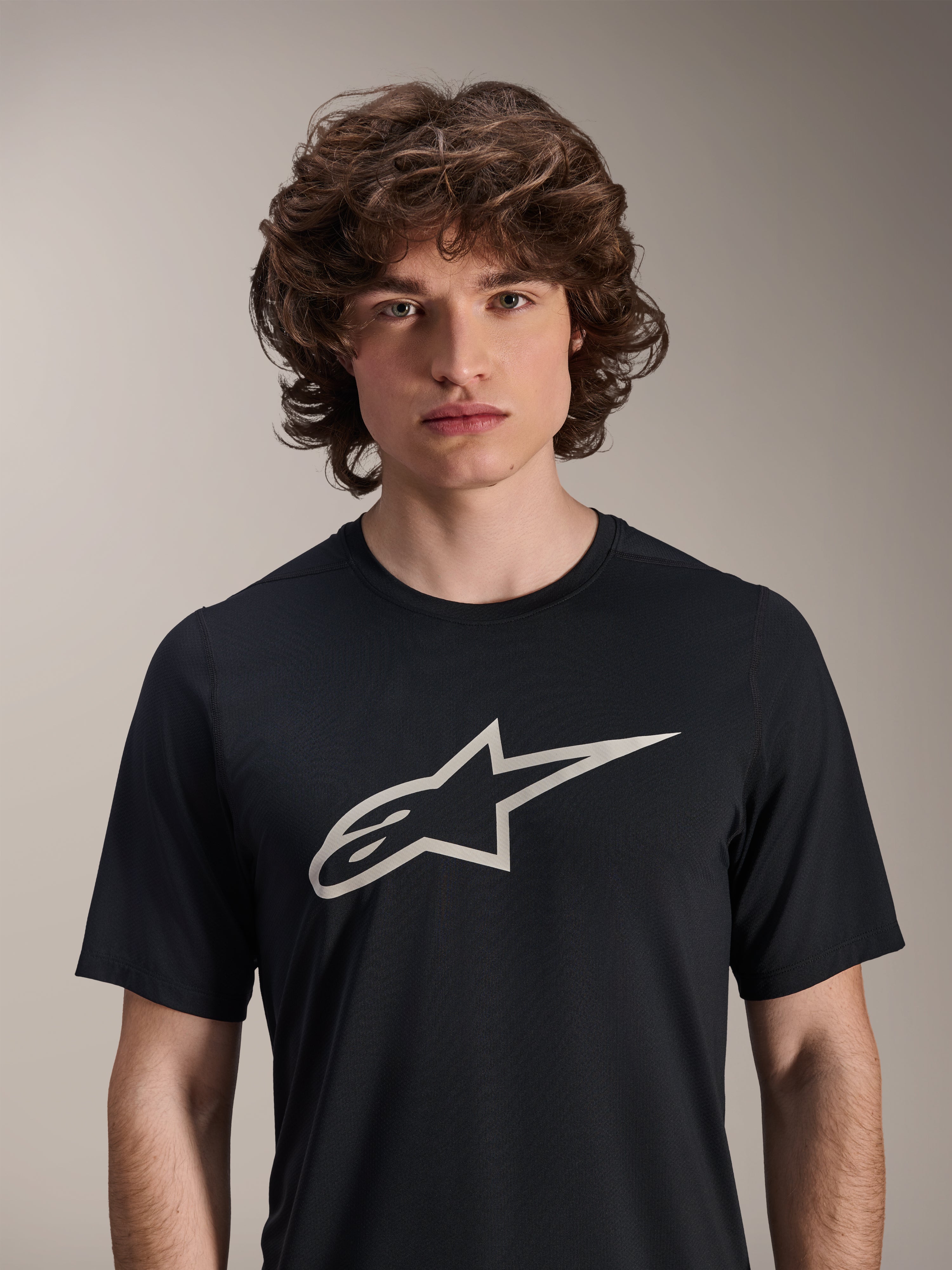 Alpinestars A-Dura Astar Short Sleeve Jersey, preta, com um grande logótipo Astar branco no peito, vestida por um modelo masculino, vestuário de performance casual para BTT