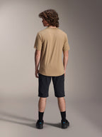 Male model from behind wearing Alpinestars A-Dura Liner Shorts in Black and a tan short-sleeve jersey, paired with black socks and shoes, durable mountain bike apparel for off-road cycling.