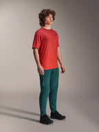 Modelo a usar calças Alpinestars A-Dura em Dark Pine, combinadas com uma camisola de manga curta A-Dura Rise vermelha e sapatos de BTT pretos, vestuário desportivo de mountain bike em ambiente de estúdio.