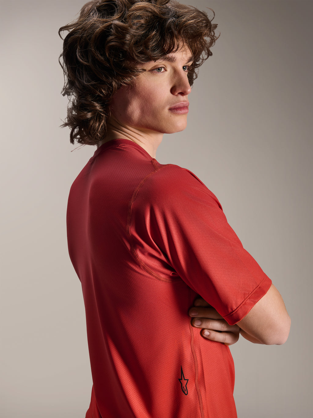 Alpinestars A-Dura Rise Jersey - Manga Curta, Spicy Orange, vista lateral e de costas do modelo, mostrando um pequeno logótipo Astars preto na bainha inferior, tecido jacquard texturizado leve para performance em BTT