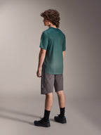 Alpinestars A-Dura Rise Jersey, Short Sleeve MTB Jersey, Silver Pine Green, worn with gray shorts and black shoes, rear view showing longer drop tail and regular fit, lightweight moisture-wicking fabric for trail riding