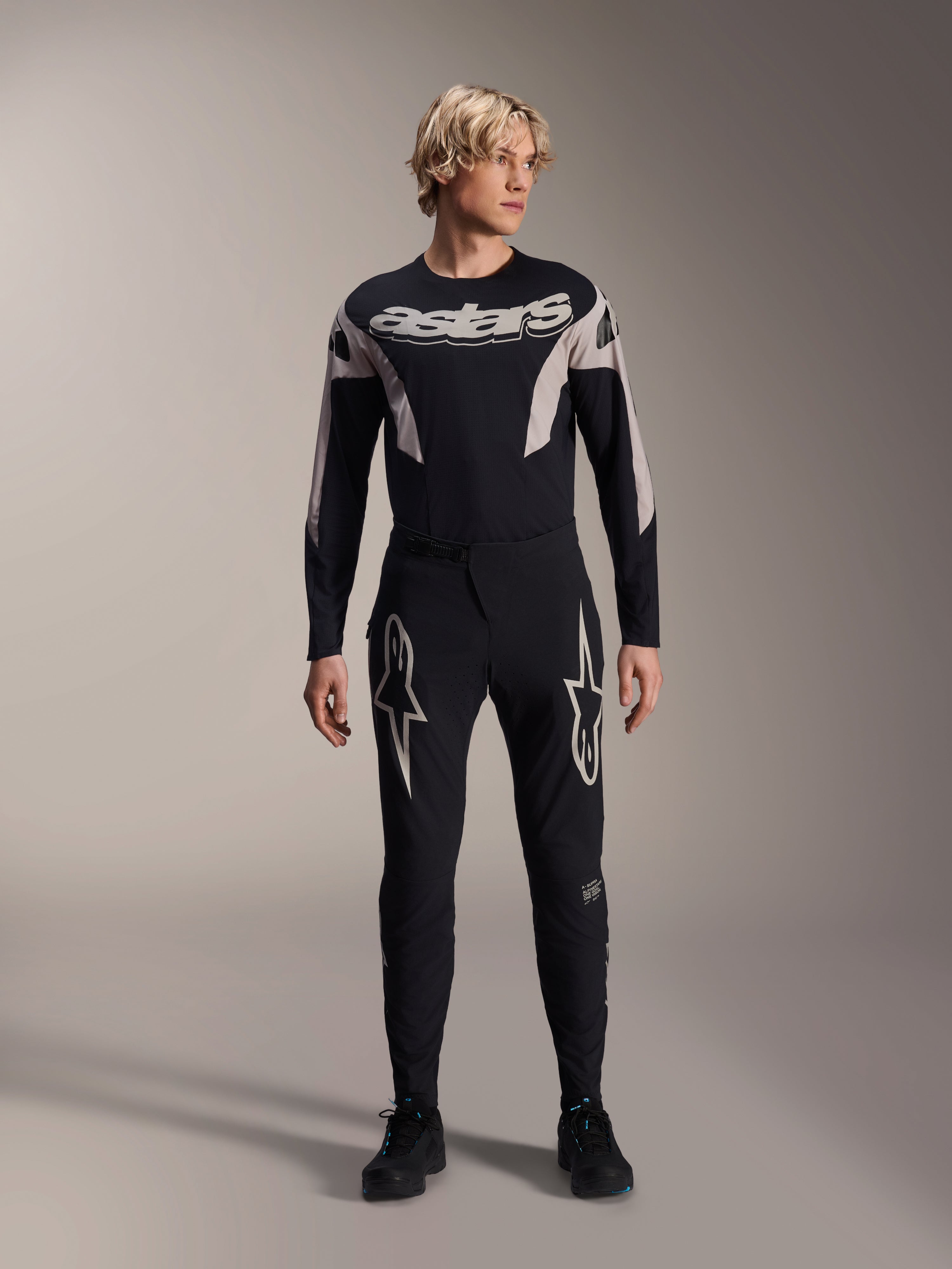 Alpinestars A-Supra Melt Pants e camisola de manga comprida a condizer, modelo a usar kit de BTT preto com gráficos de estrelas brancas grandes nas coxas e marca 'astars' no peito, vestuário profissional de corrida de BTT