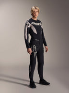 Modelo masculino a vestir a camisola Alpinestars A-Supra Melt - Manga Comprida, preta com pormenores gráficos cinzentos, logótipo 'astars' no peito, combinada com calças e sapatos pretos a condizer, kit de performance de mountain bike para corridas fora de estrada