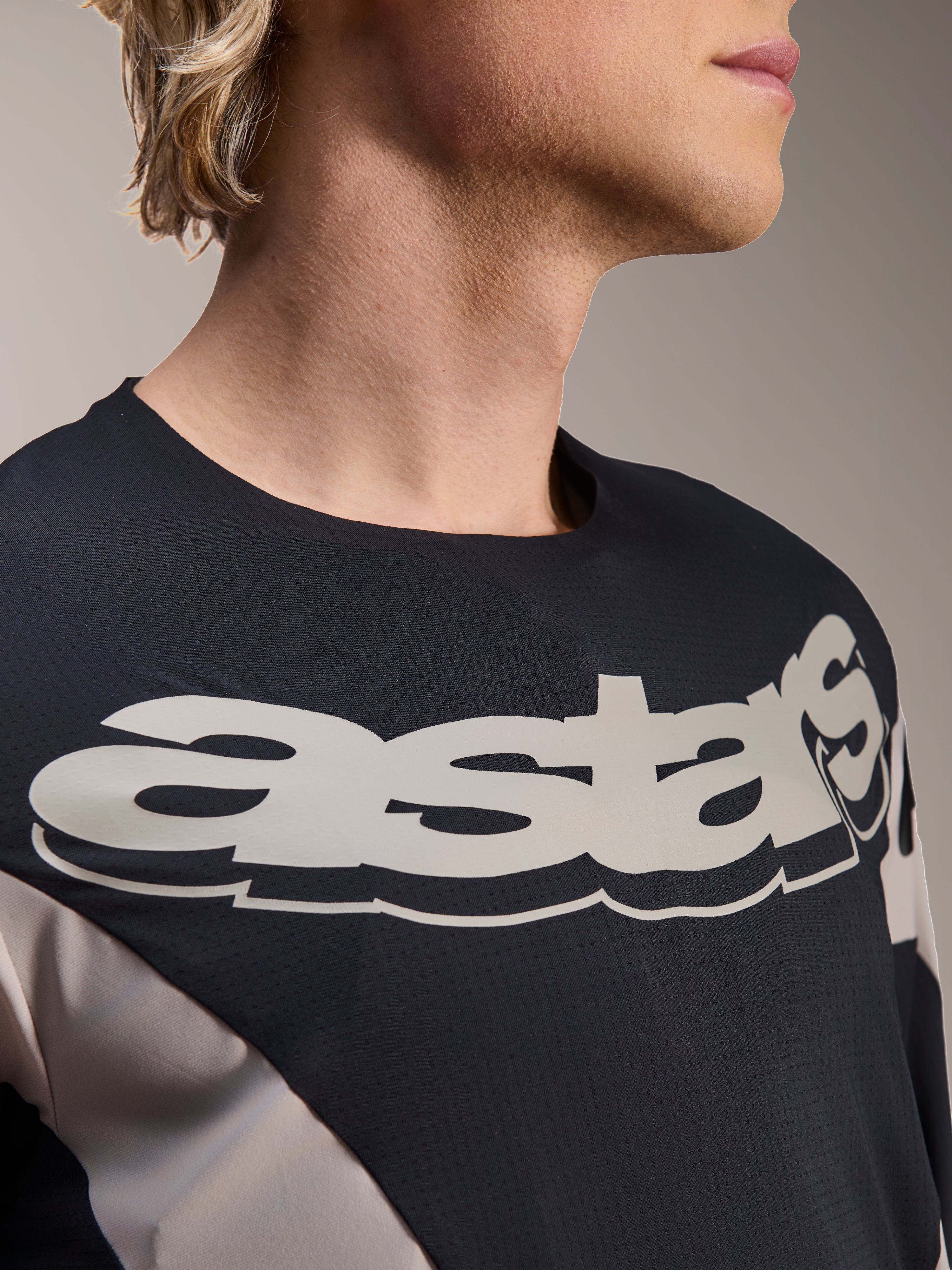 Jersey Alpinestars A-Supra Melt, jersey de MTB de manga comprida, preto e cinzento com logótipo "astars" branco de grandes dimensões no peito, tecido microperfurado respirável, design inspirado na competição