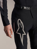 Calças Alpinestars A-Supra Melt, calças de BTT, pretas, com um grande logótipo Astar branco na coxa, fecho de catraca ajustável na cintura e bolso lateral com fecho de correr, vista detalhada de equipamento técnico de performance para BTT