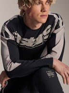 Alpinestars A-Supra Melt Jersey, camisola de BTT de manga comprida, preta com grafismos cinzento-claro, usada por modelo, com logótipo de destaque no peito e branding 'One Goal. One Vision.', vestuário de performance para BTT
