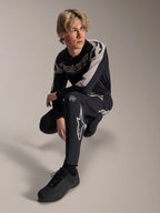 Calças e Jersey de Manga Comprida Alpinestars A-Supra Melt, pretas e cinzentas, com marca branca e logótipos de estrela em destaque, modelo masculino em pose agachada, equipamento de BTT coordenado