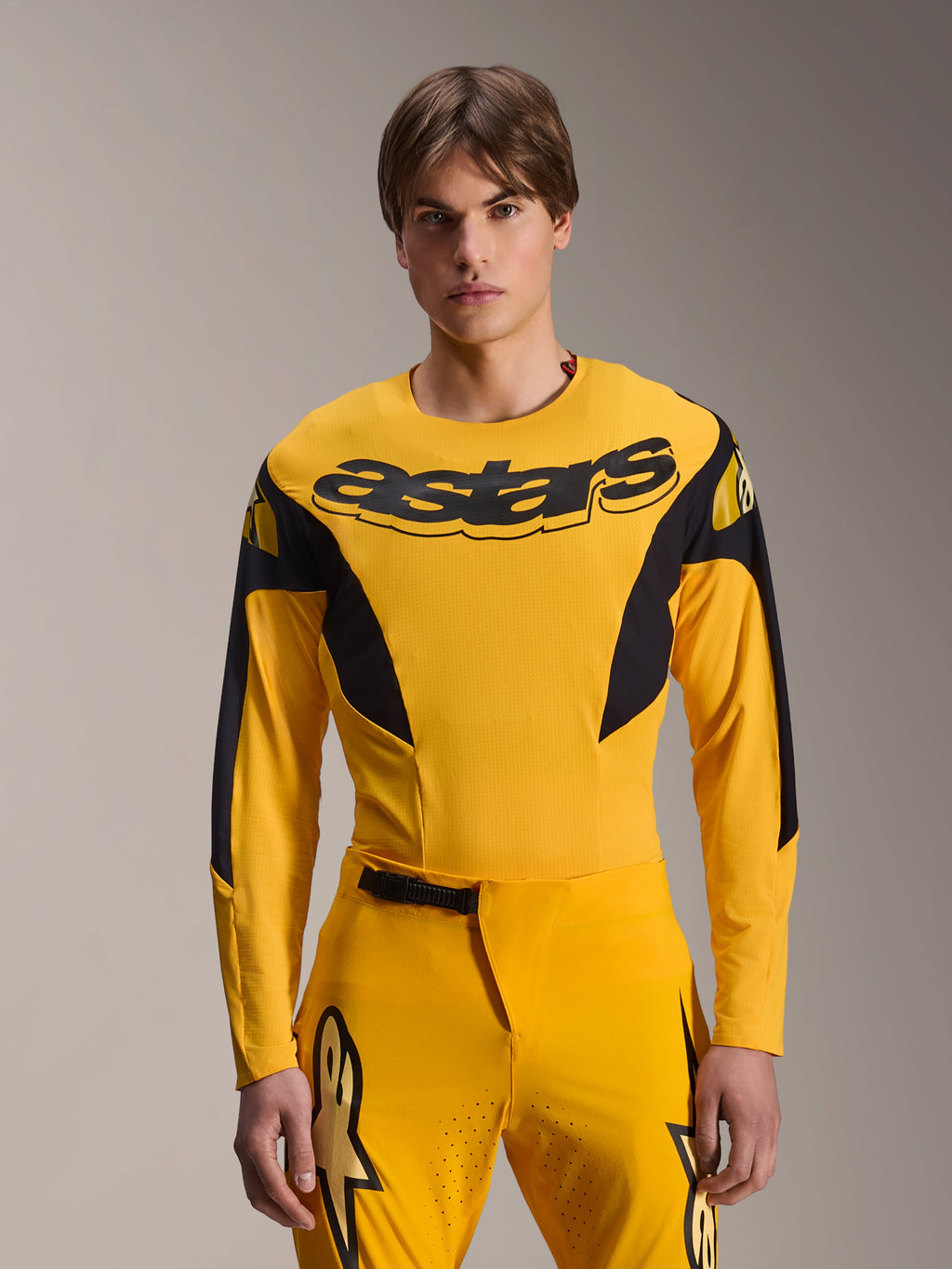Alpinestars Limited Edition A-Supra Melt Gold Jersey, camisola de BTT de manga comprida, amarela escura com detalhes pretos, vestida por um modelo com calças a condizer, com um grande logótipo "astars" preto no peito e design de performance atlética