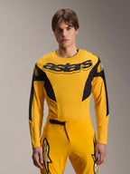 Alpinestars Limited Edition A-Supra Melt Gold Jersey, camisola de BTT de manga comprida, amarela escura com detalhes pretos, vestida por um modelo com calças a condizer, com um grande logótipo "astars" preto no peito e design de performance atlética